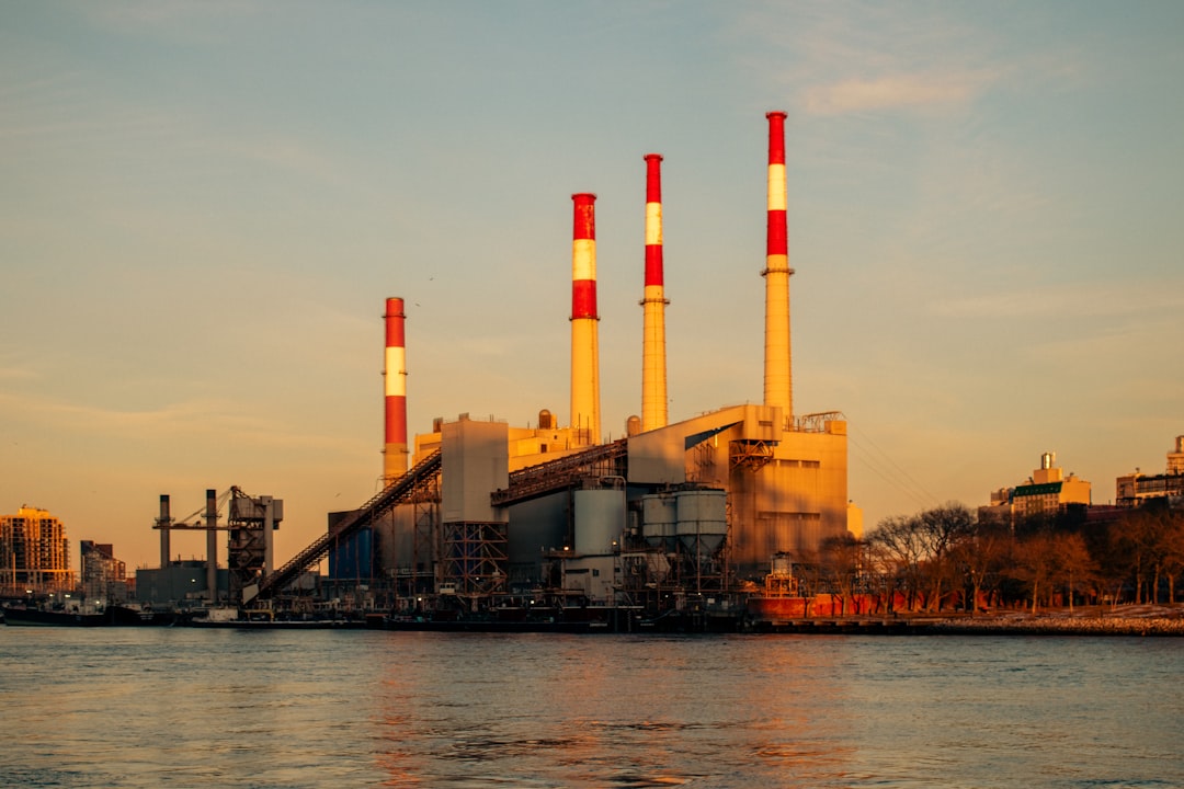 A power plant with tall smokestacks by the water.