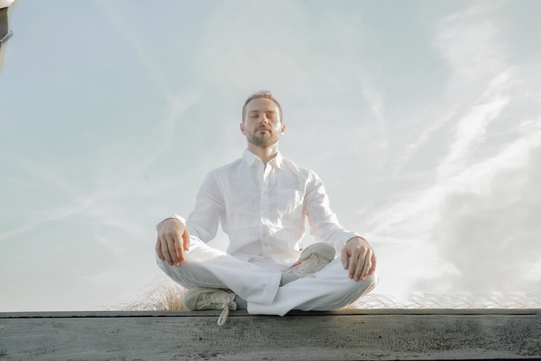 A man in a white shirt and tie sitting in a lotus position