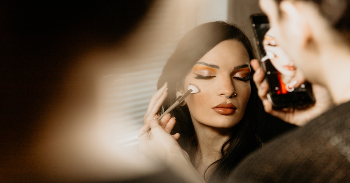 Коричневая тушь для ресниц на кисточке на фоне косметики