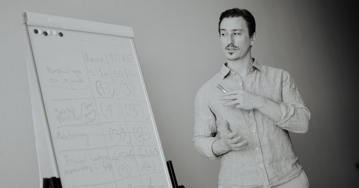 Предприниматель работает над созданием нового продукта, на столе эскизы, прототип и ноутбук