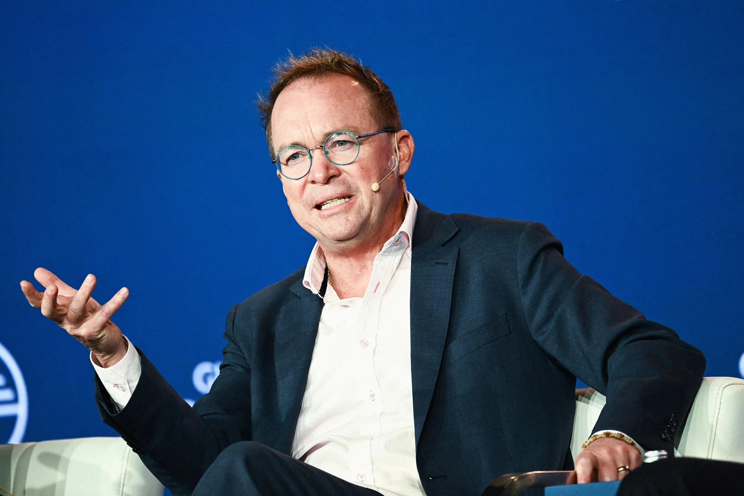 Деловой человек выступает на пресс-конференции или участвует в дискуссии на фоне флагов