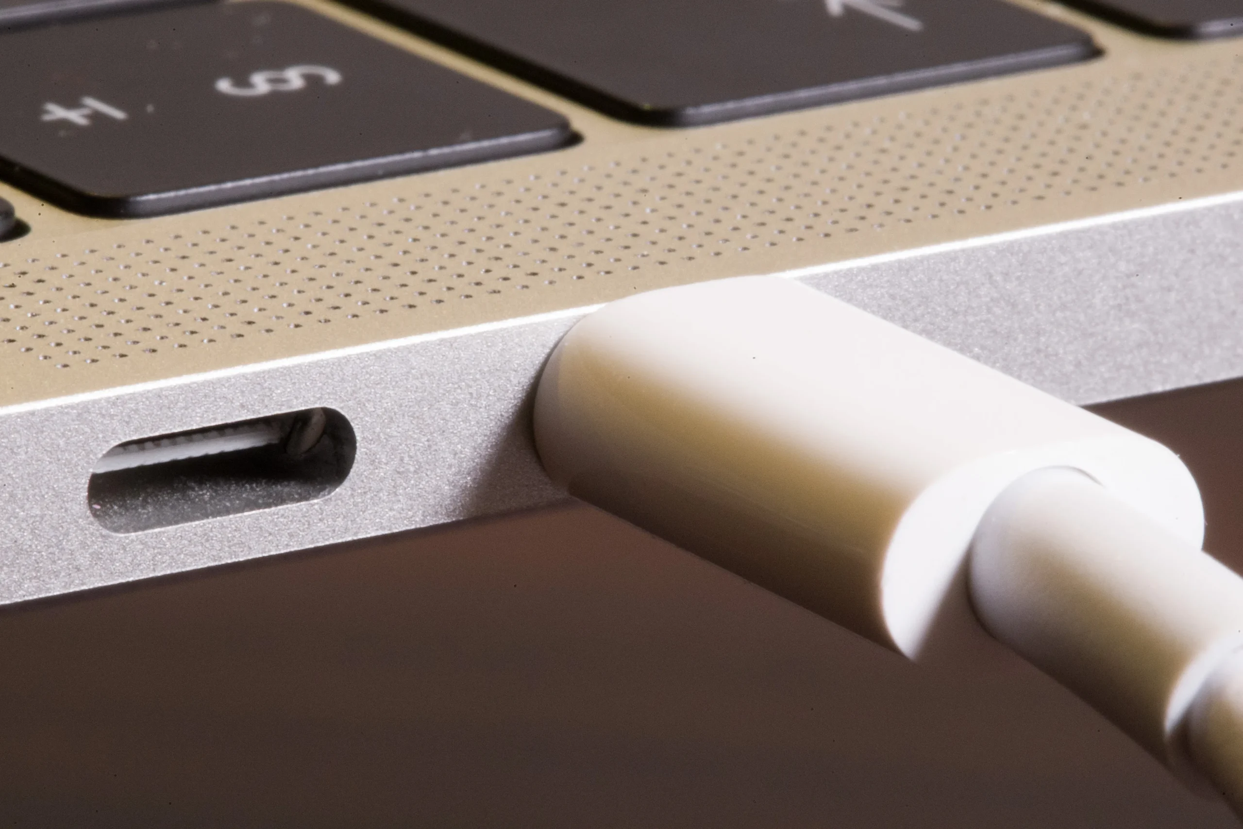 Ноутбук MacBook, подключённый к зарядному устройству, на рабочем столе